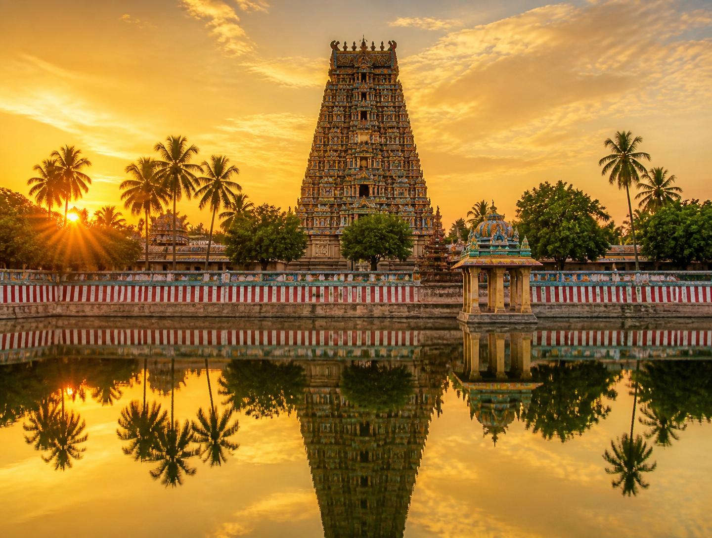 South Indian temple gopuram reflected in a calm temple pond at sunrise
